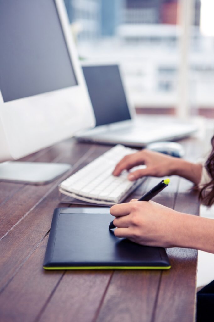 Feminine hands using digital board and computer keyboard in office