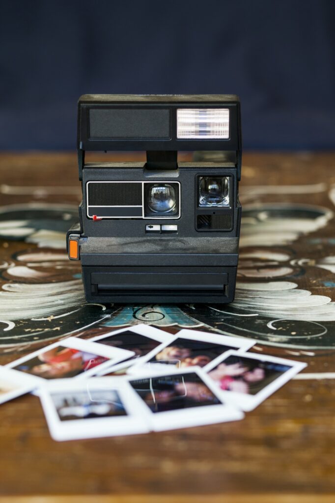 Instant camera and photographs on wooden table